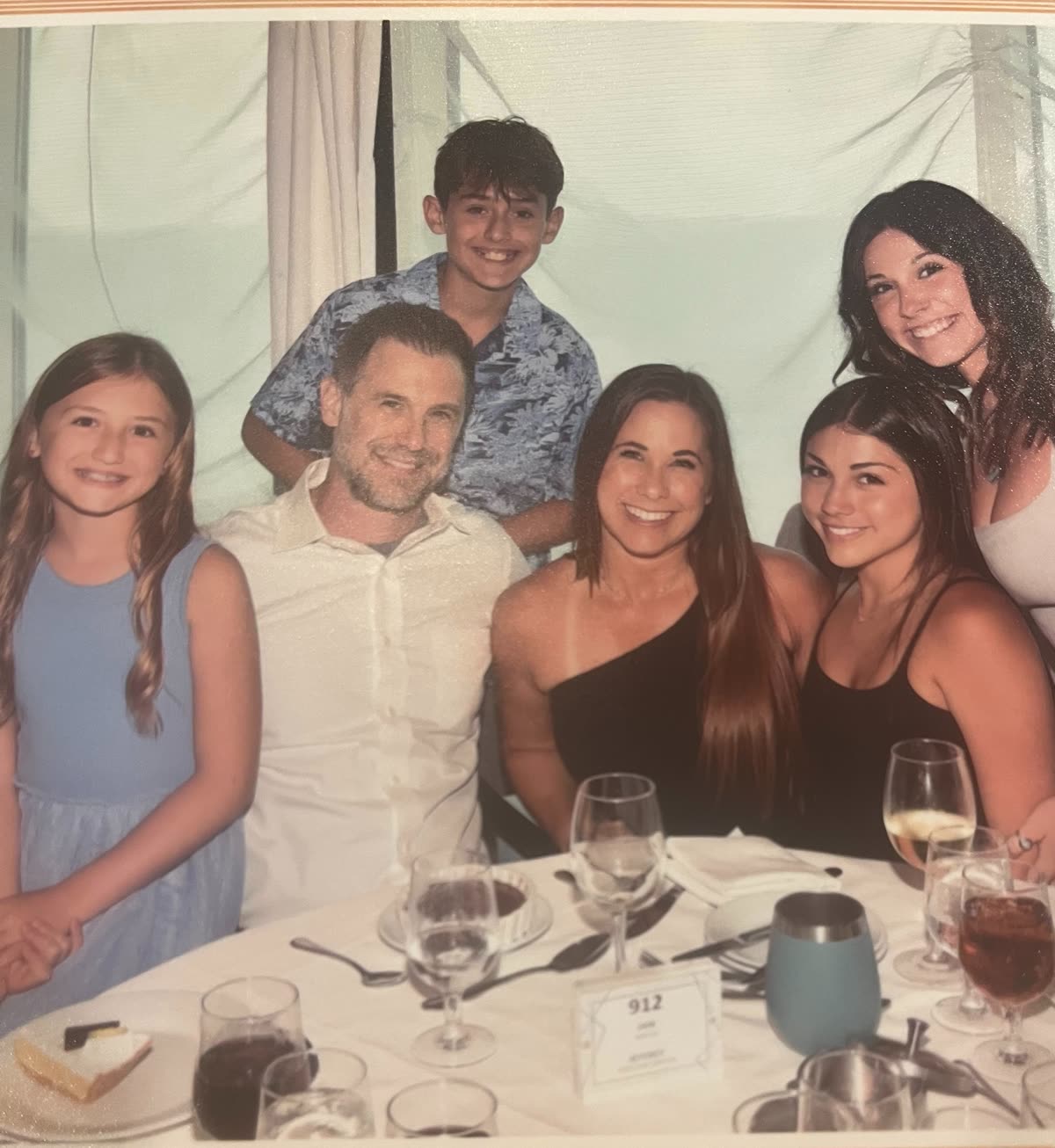 The Baker family seated together around a dinner table, all six of them smiling.